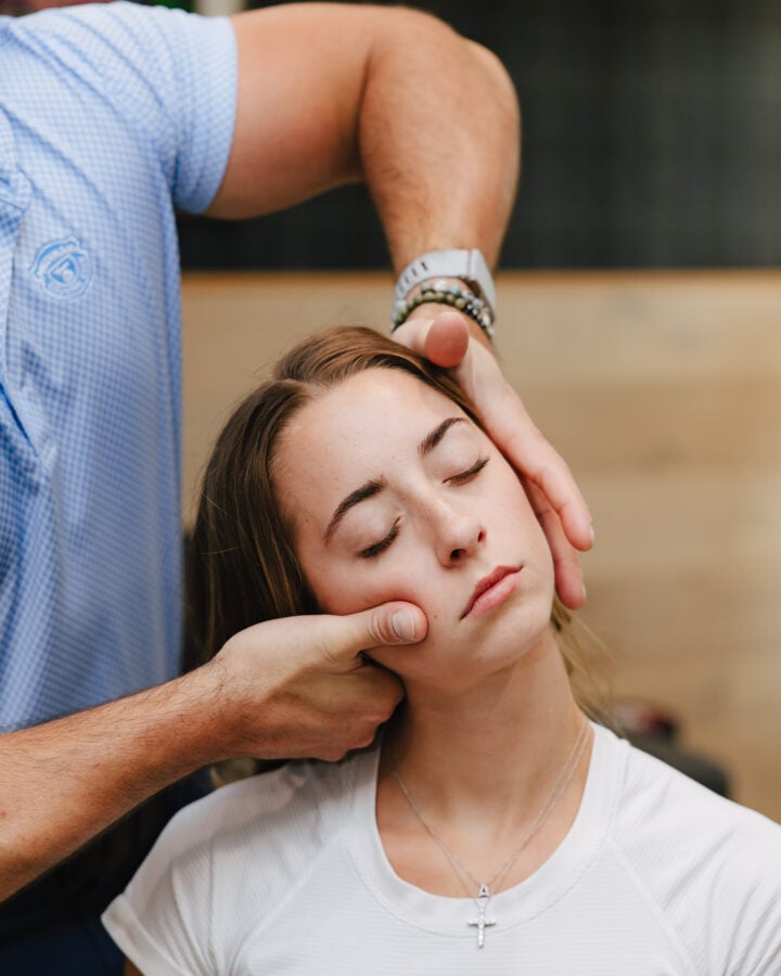 Chiropractor performing a gentle neck and jaw assessment on a patient at Forza Chiropractic